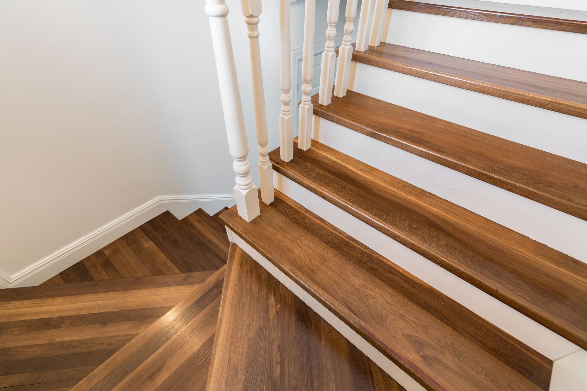 A close up of a wooden staircase with a white railing.