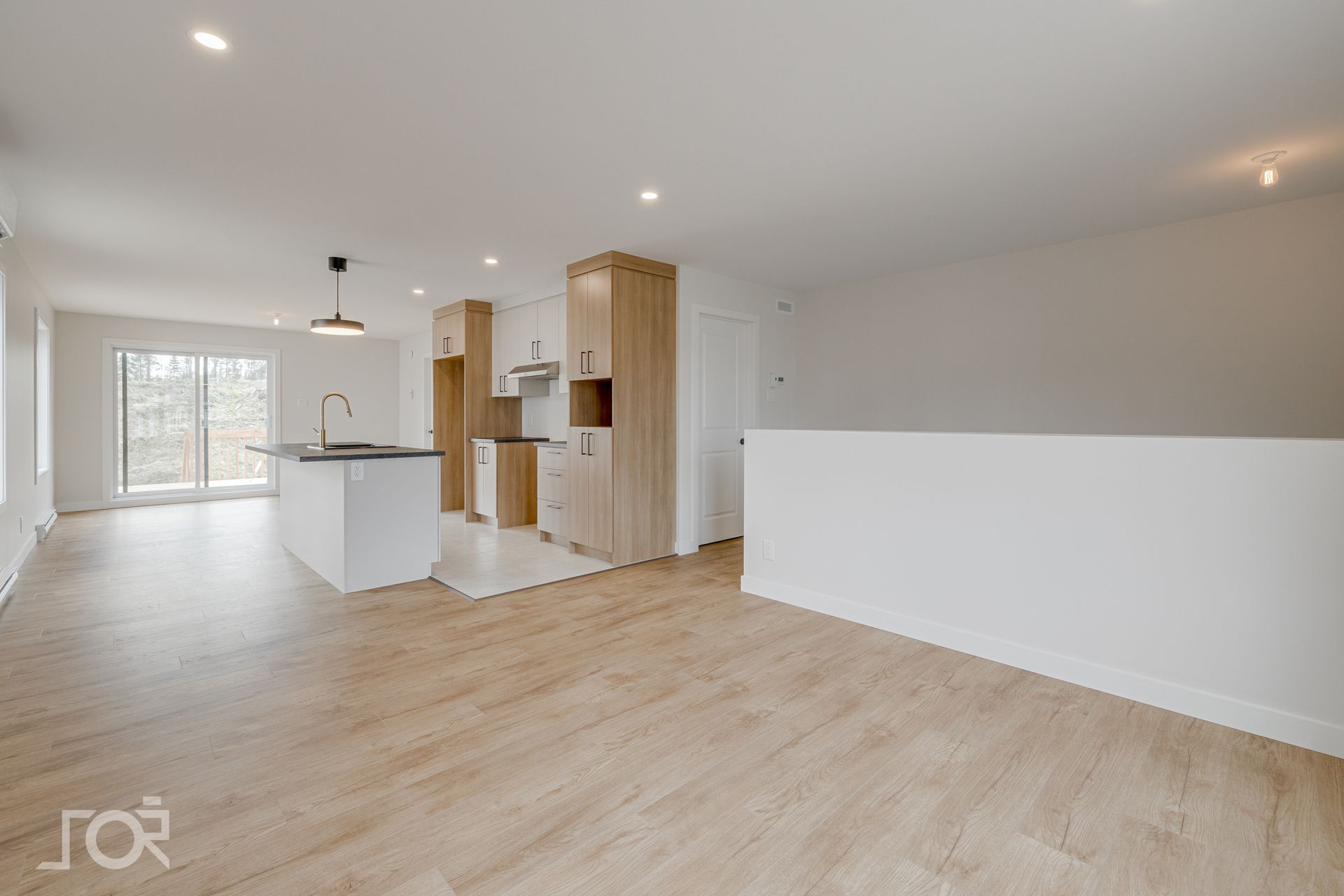 Une pièce vide avec du parquet et des murs blancs.