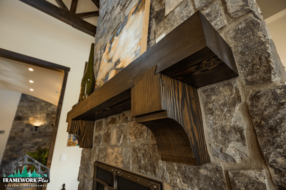 A fireplace with a wooden mantle and a stone wall.