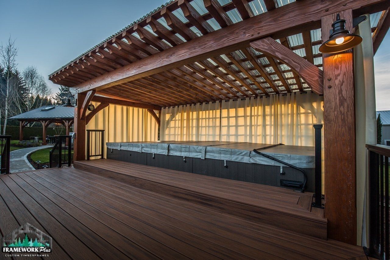 A wooden deck with a hot tub under a pergola.