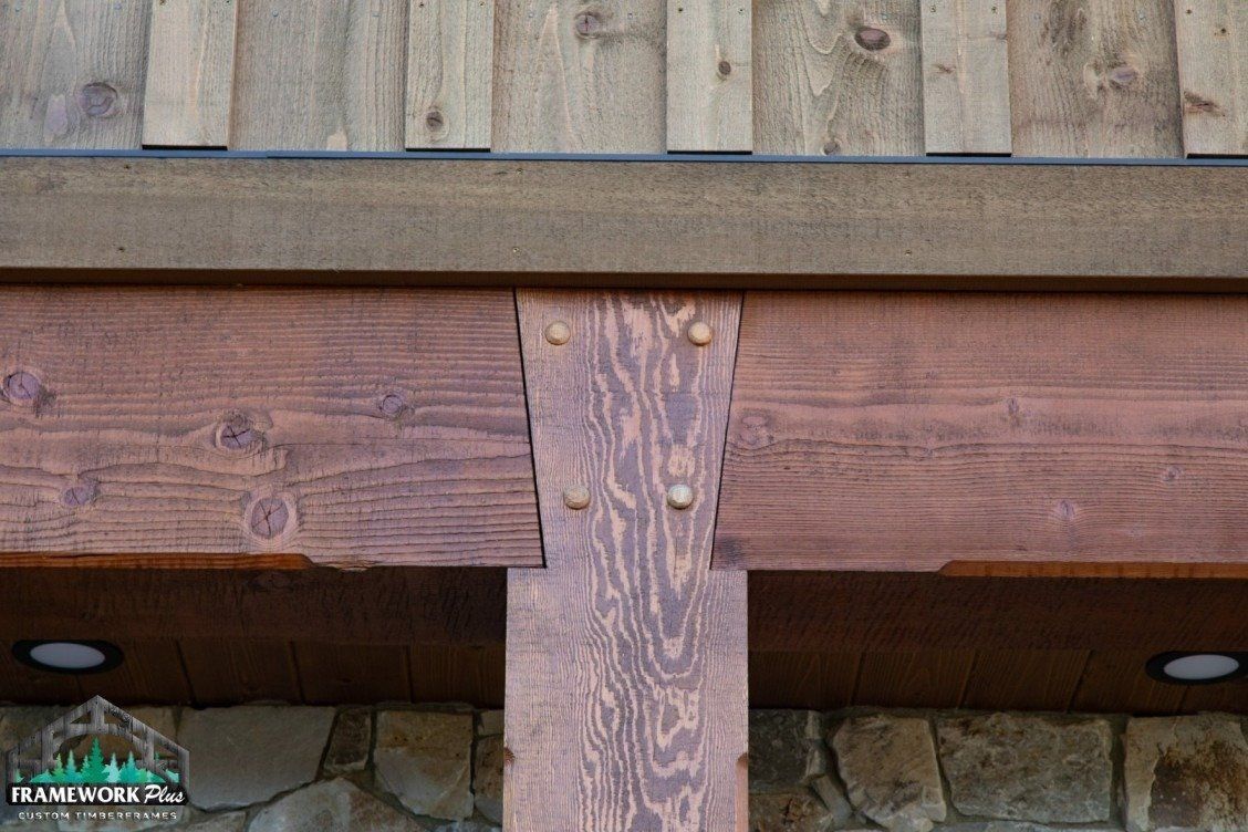 A close up of a wooden structure with a stone wall in the background.