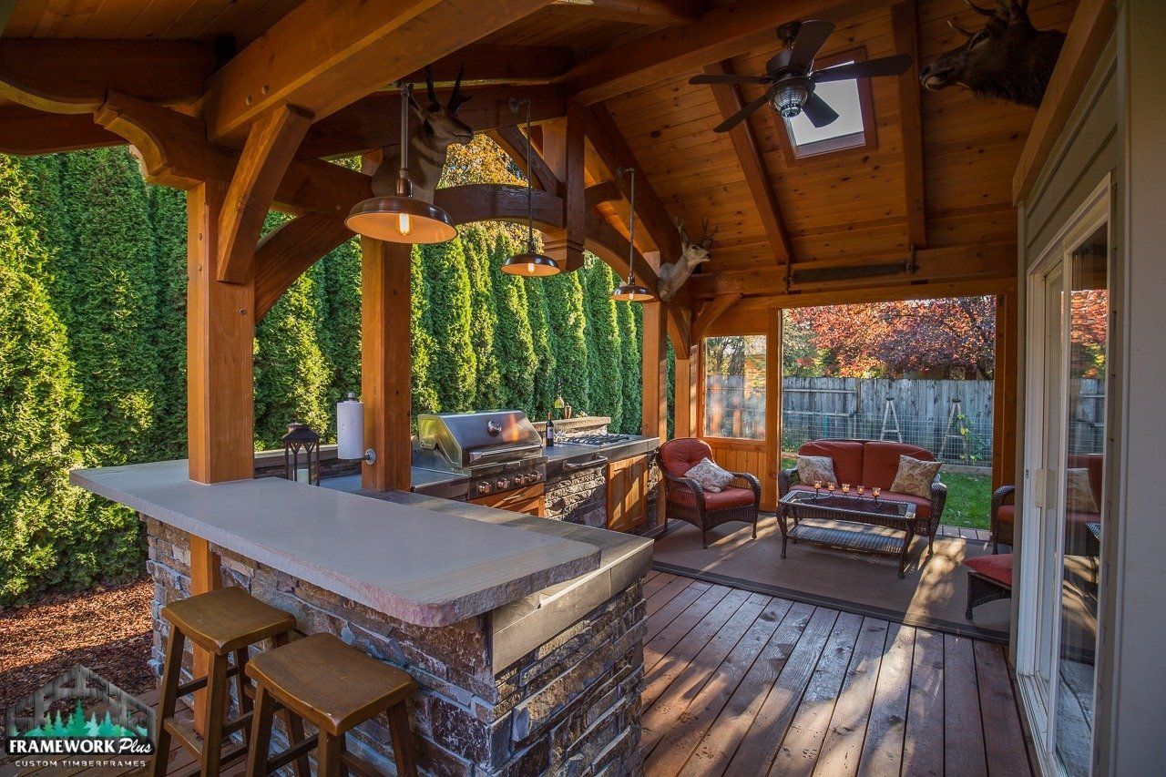 A covered patio with a bar and stools under a wooden roof.