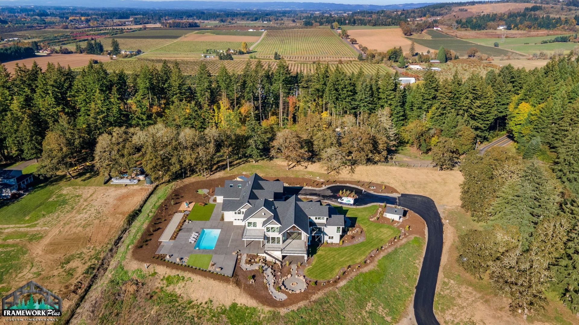 An aerial view of a large house surrounded by trees and fields.