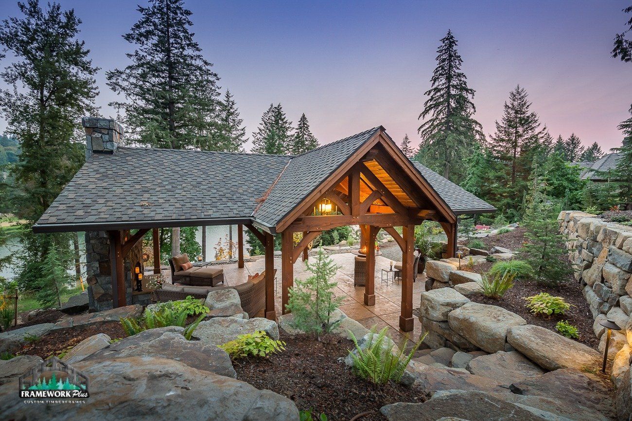 A wooden pavilion is surrounded by trees and rocks in the middle of a forest.