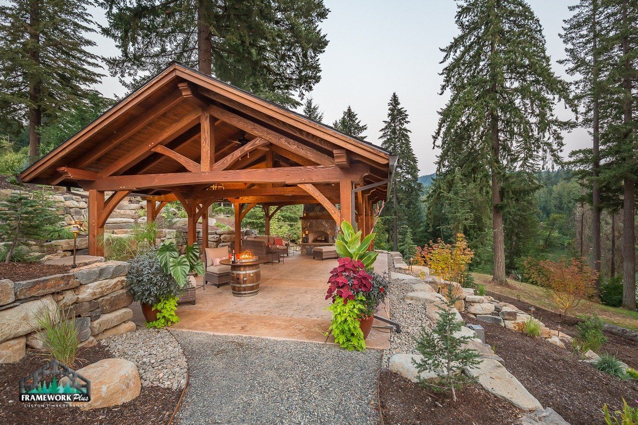 A wooden pavilion with a fire pit in the middle of a forest.