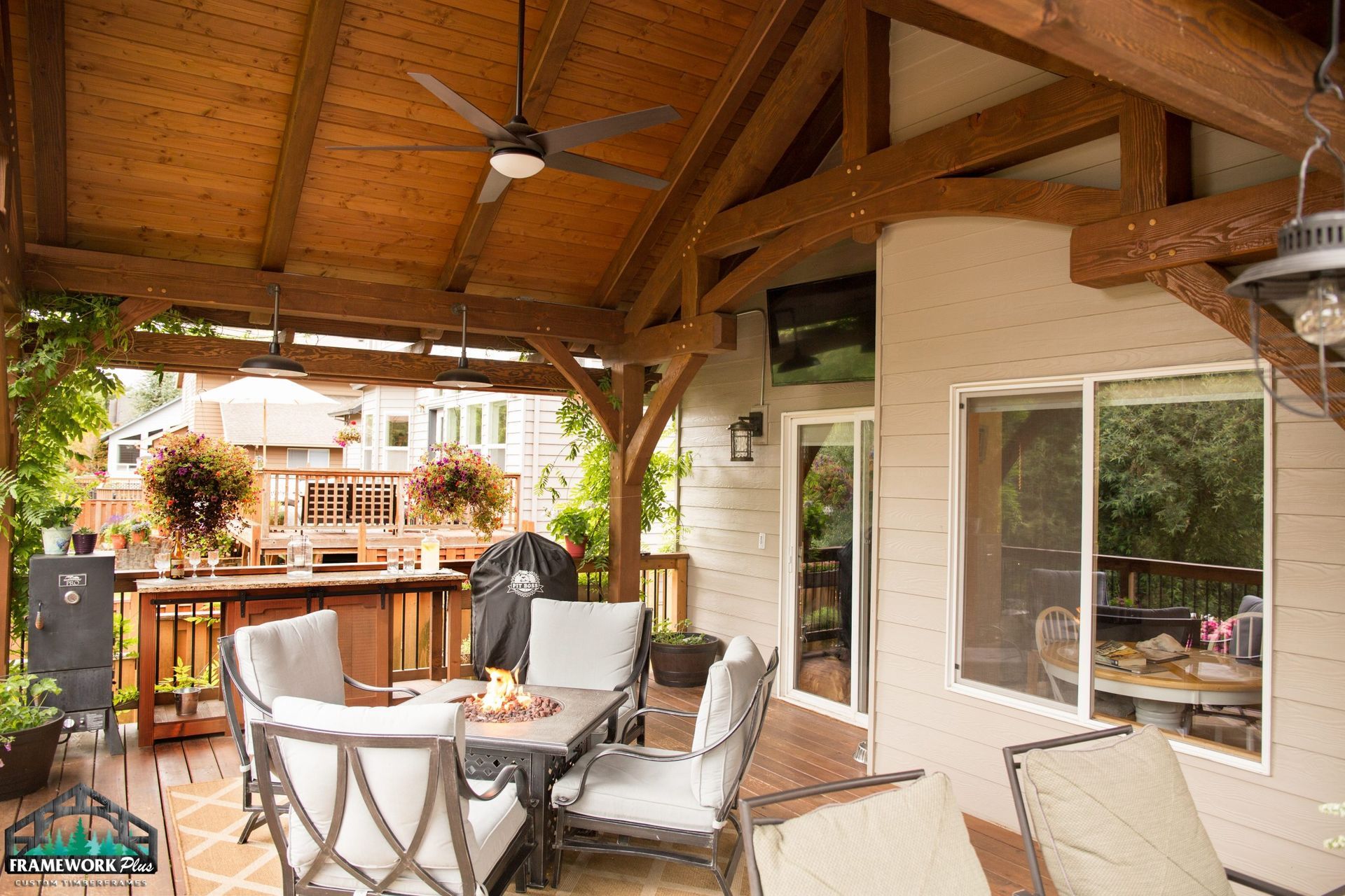 A patio with a table and chairs under a wooden roof.