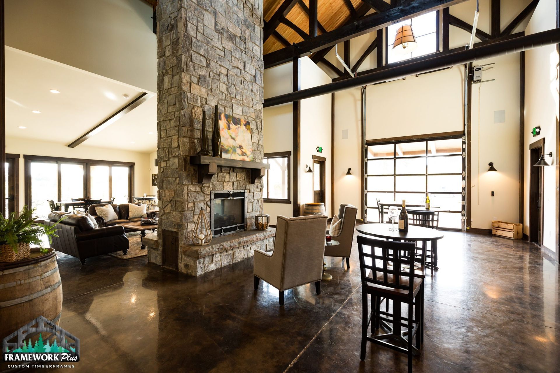 A living room with a fireplace , chairs , tables and a large stone fireplace.