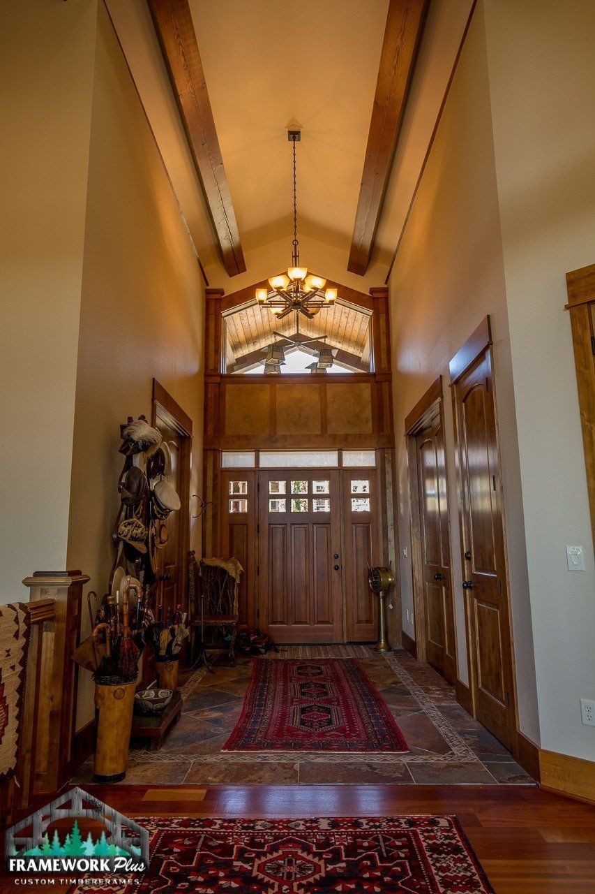 A long hallway with a wooden door and a chandelier hanging from the ceiling.