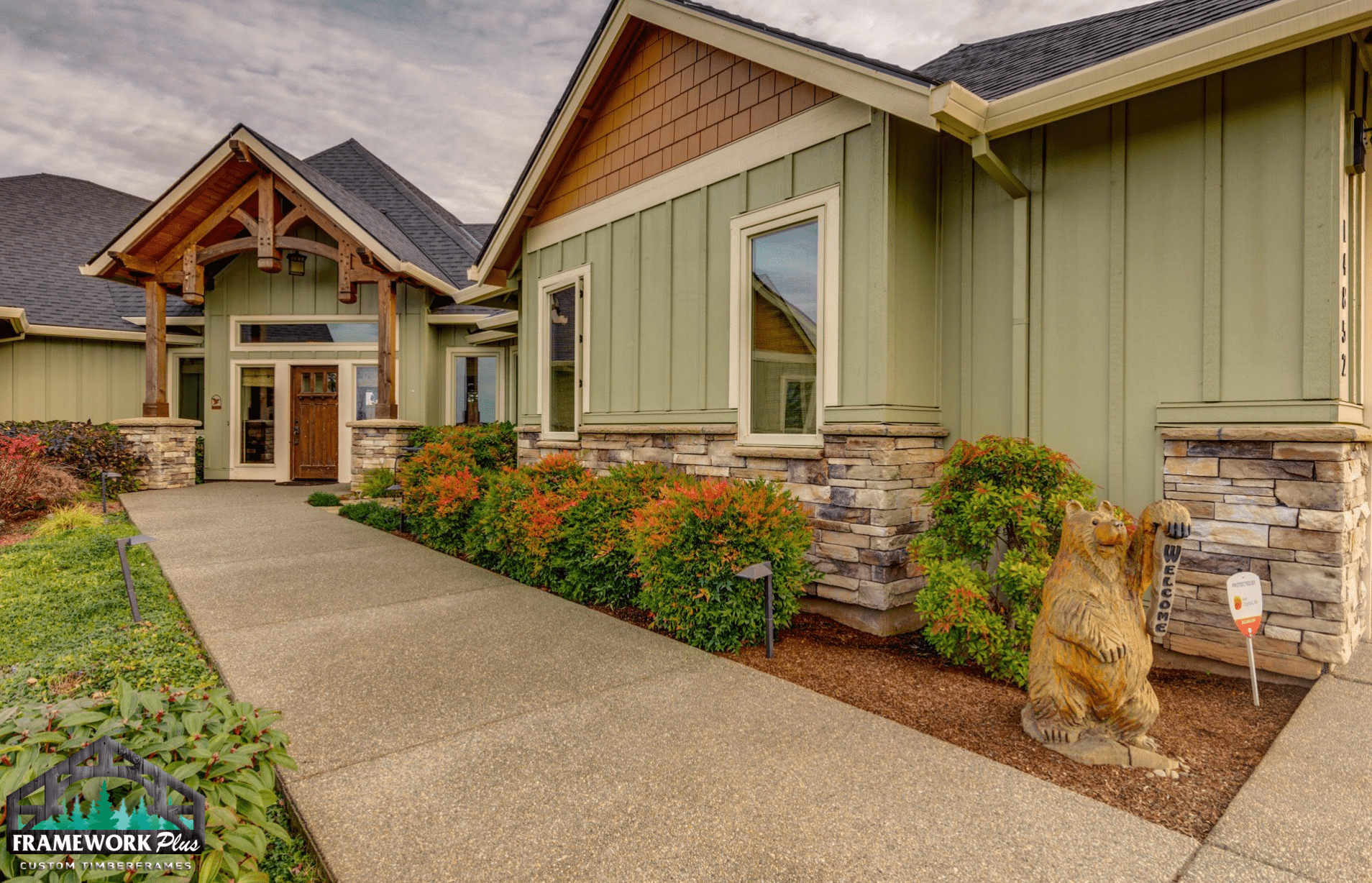 A large green house with a bear statue in front of it