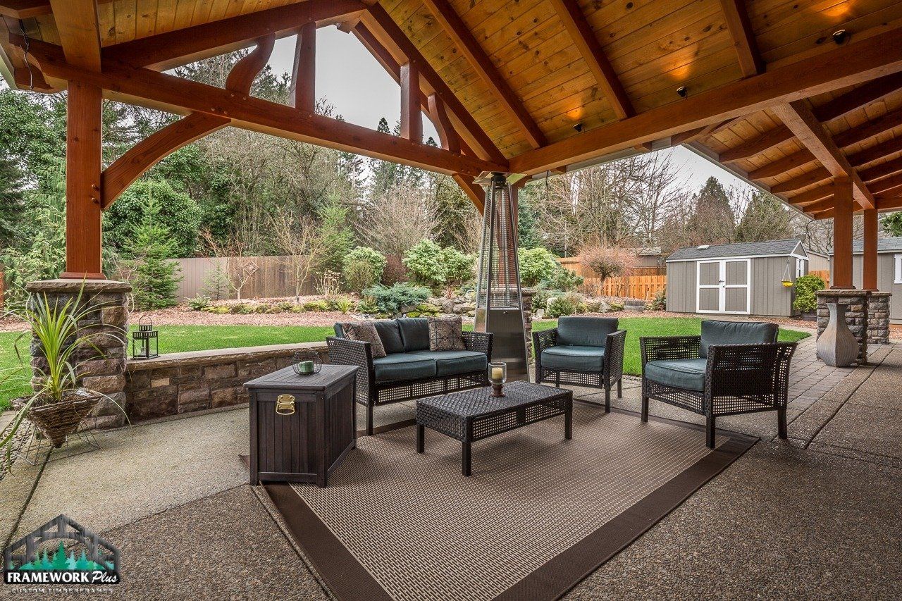 A patio with furniture under a wooden roof.