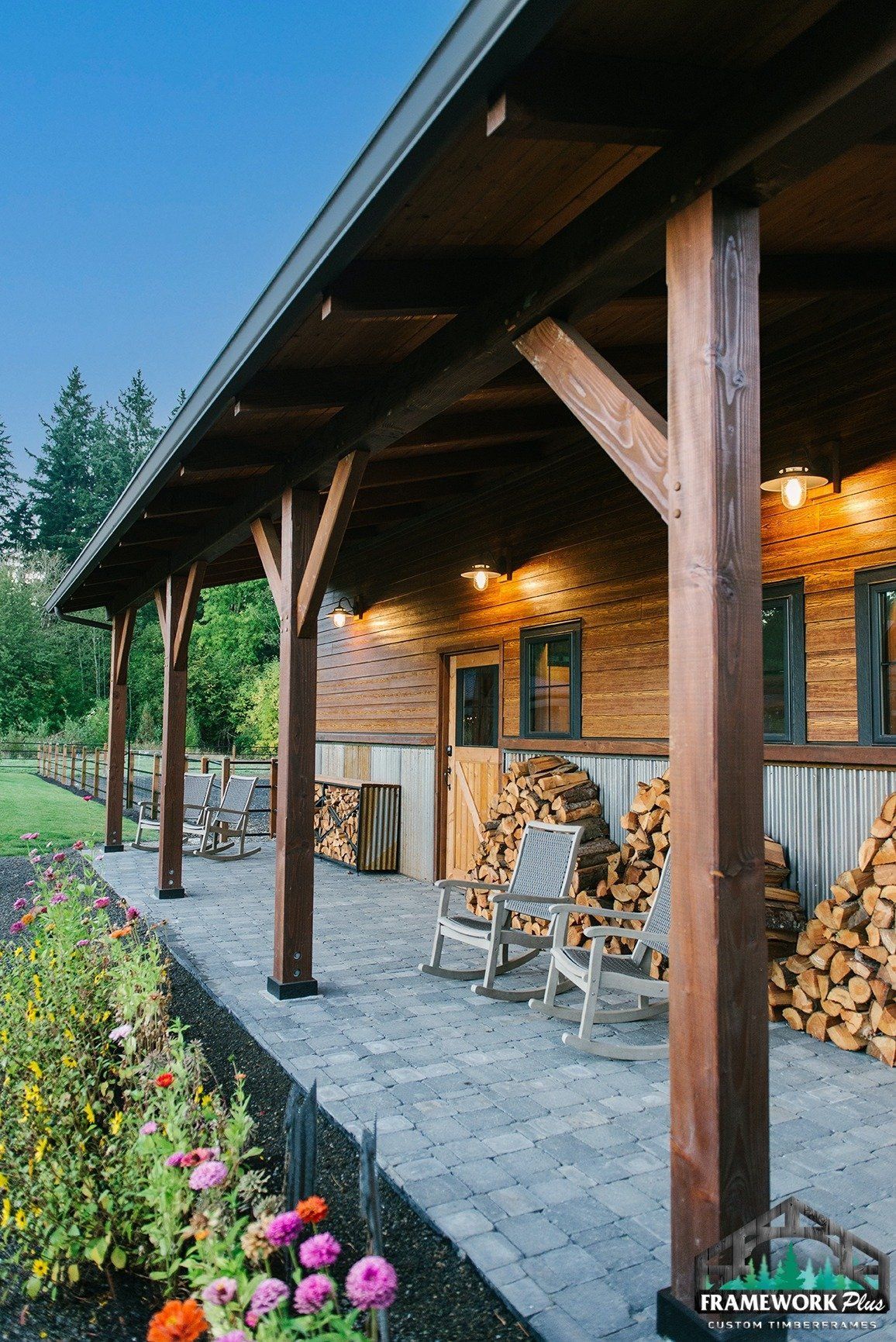 A wooden porch with rocking chairs and a pile of logs.
