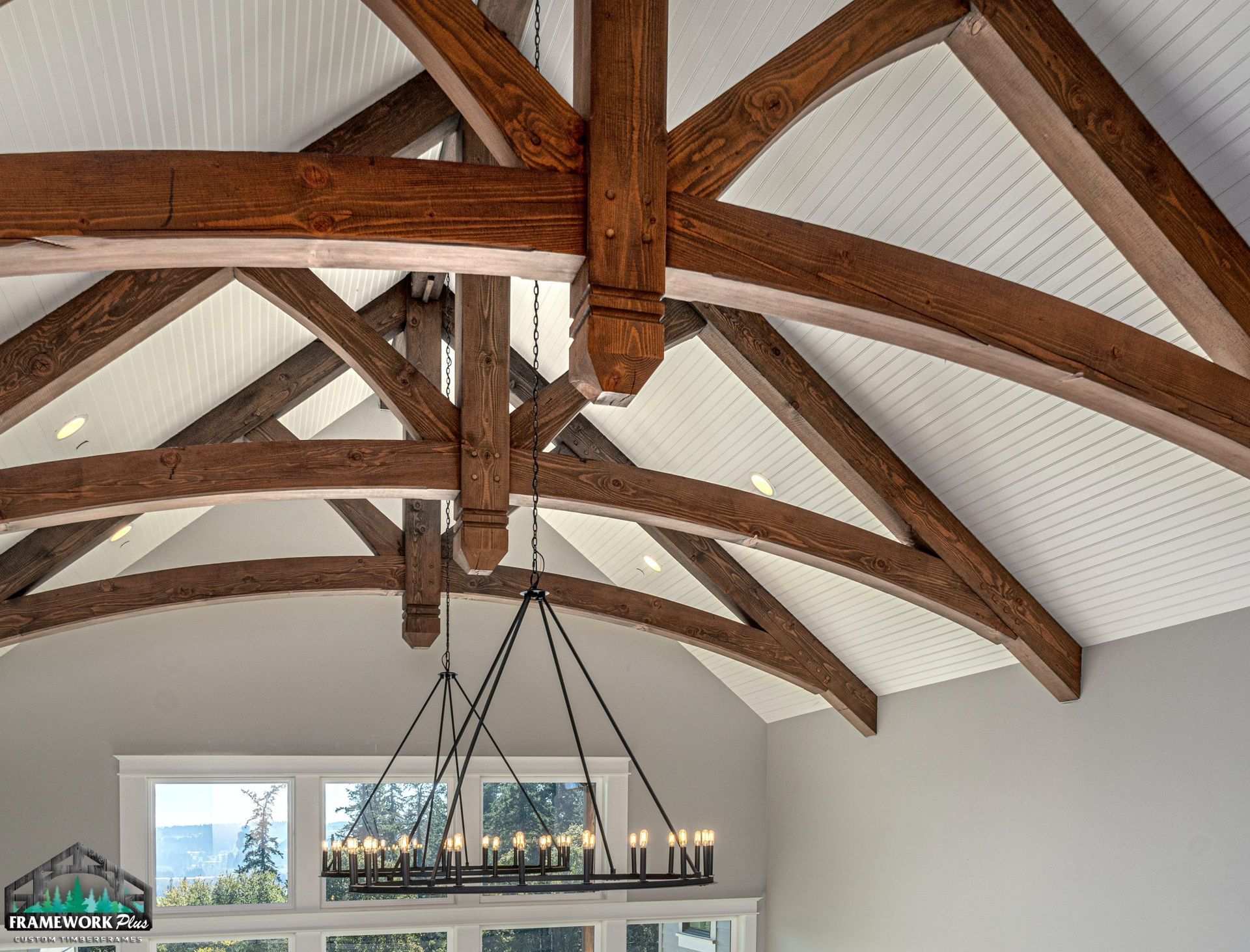 The ceiling of a house with wooden beams and a chandelier hanging from it.