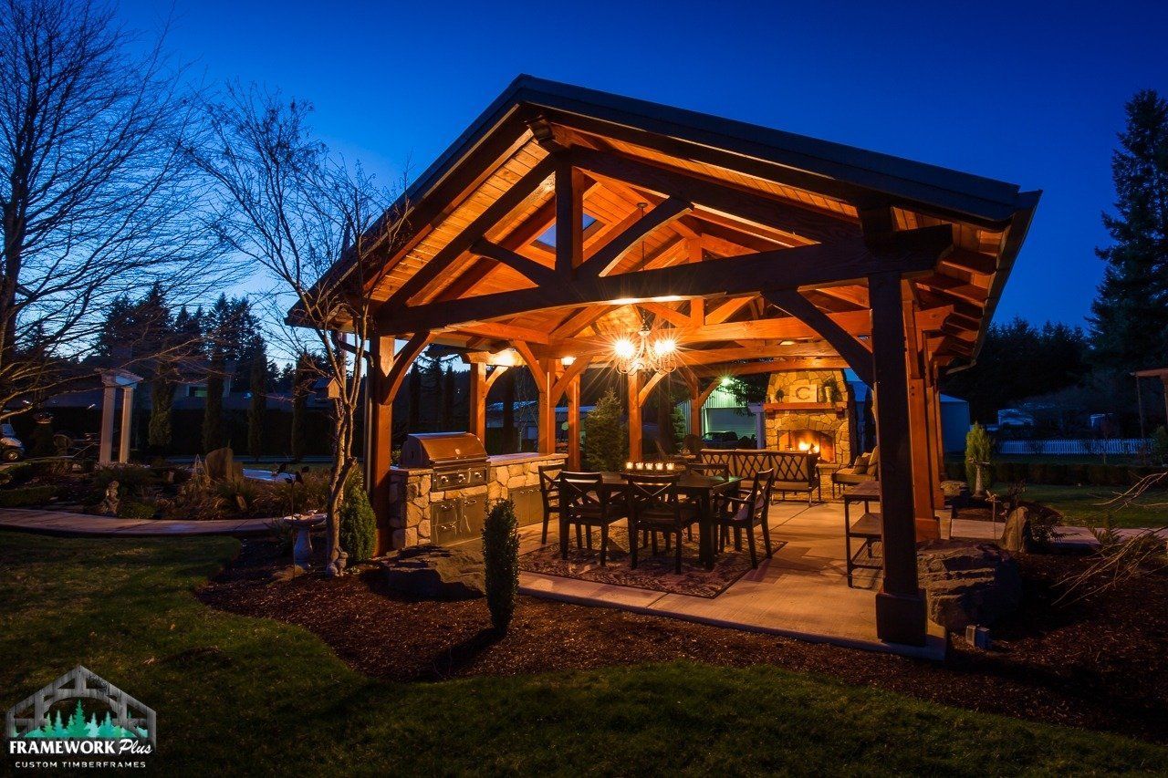 A wooden pavilion with a table and chairs underneath it at night.
