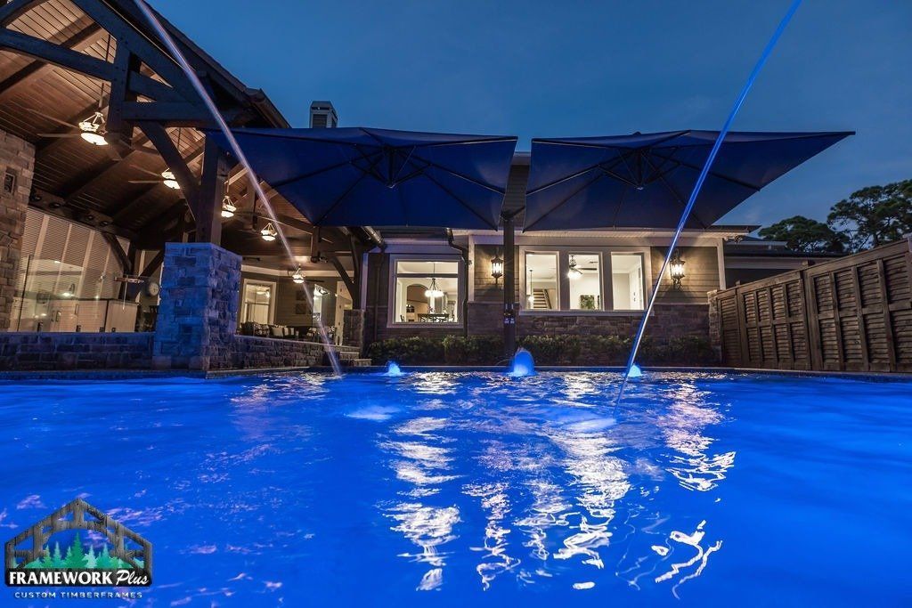 A large swimming pool is lit up at night with blue lights.