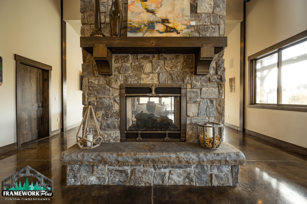 There is a large stone fireplace in the middle of the room.