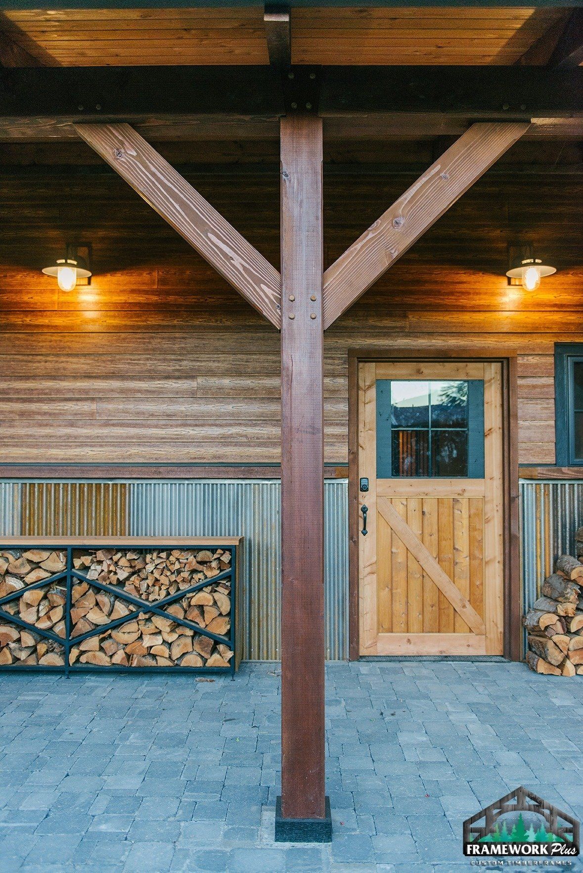 A wooden porch with a door and a pile of logs
