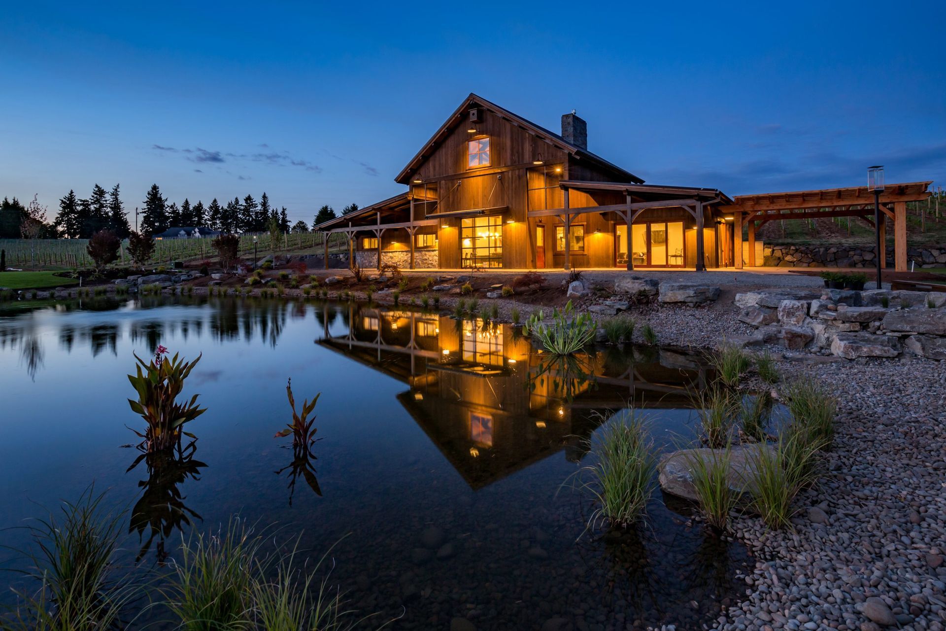 A large house is reflected in a pond at night