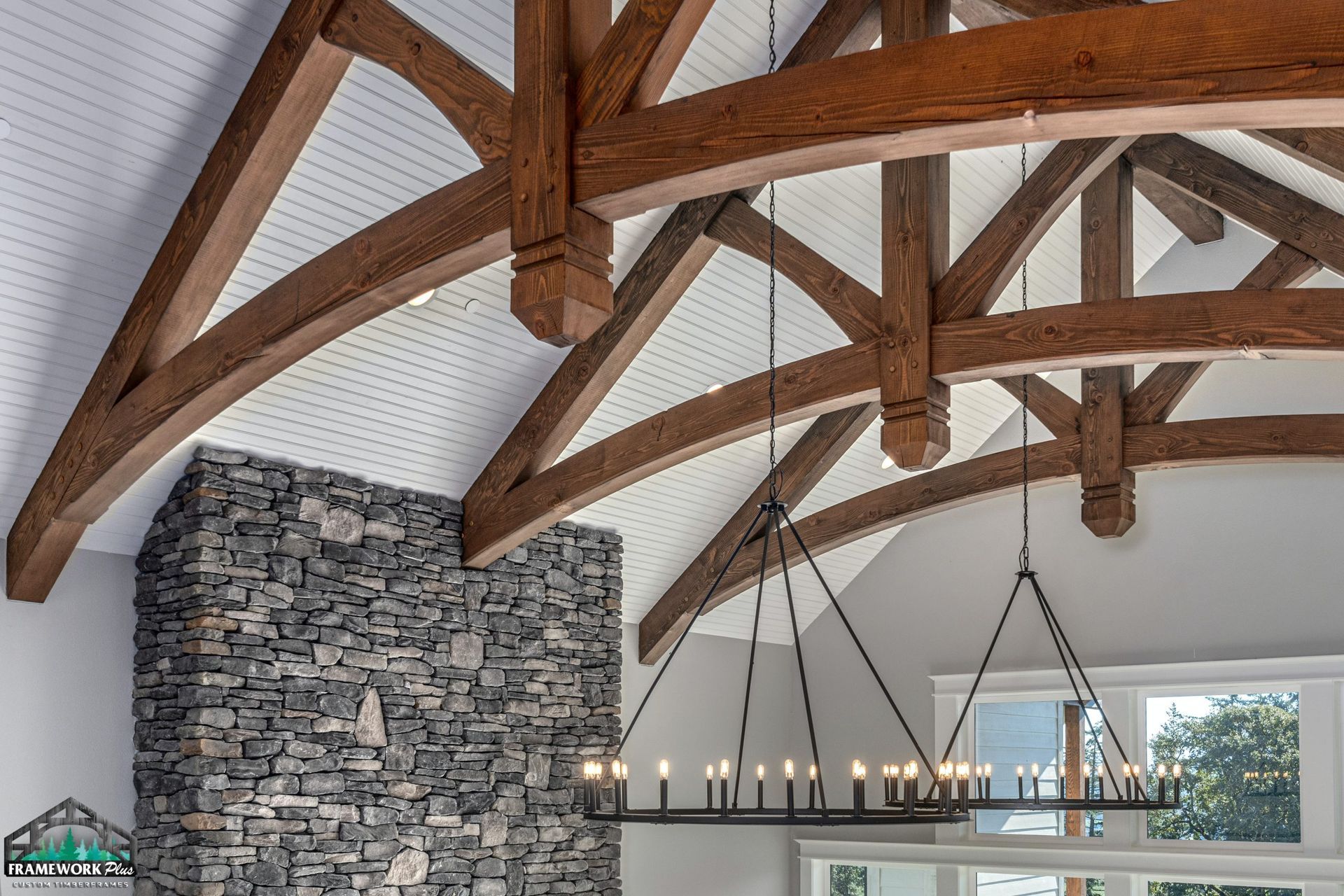 A living room with a stone fireplace and a chandelier hanging from the ceiling.