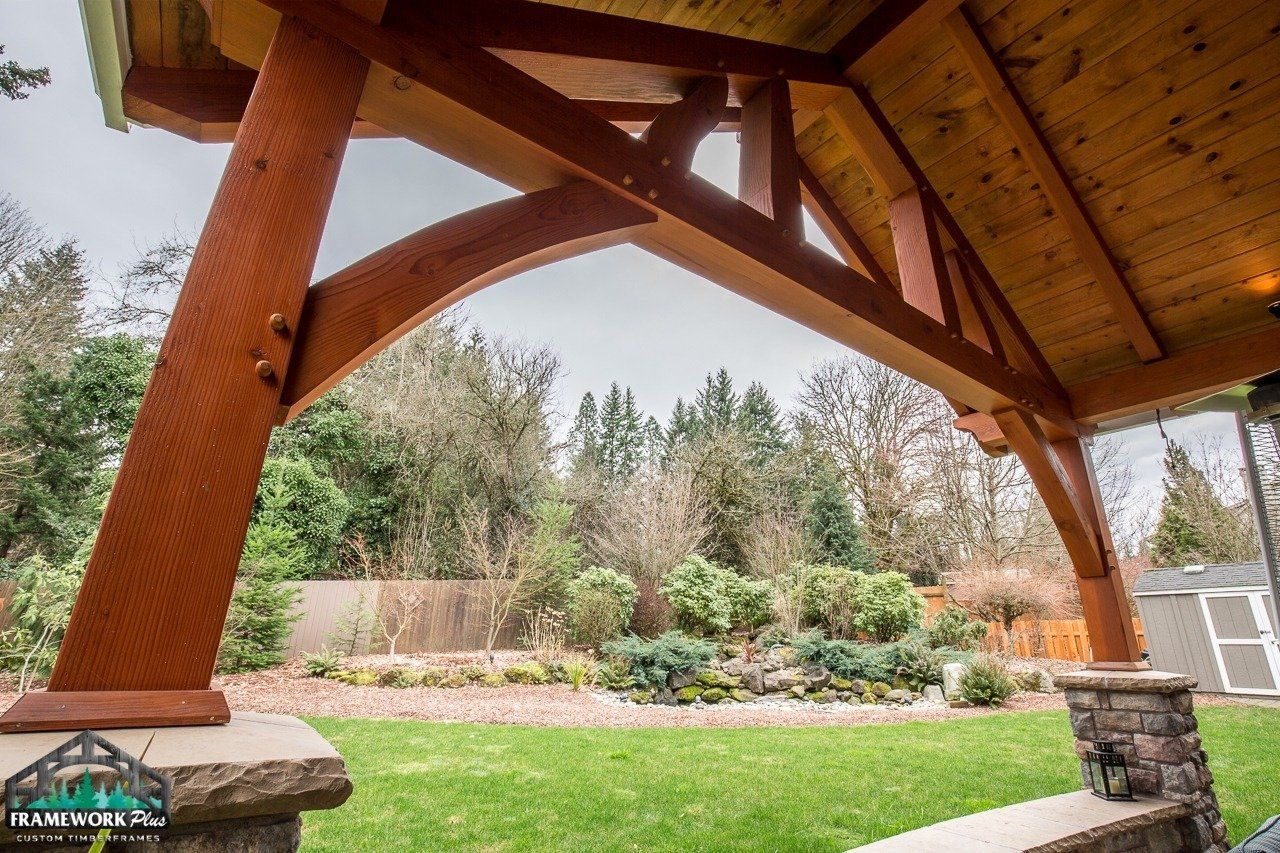 A wooden structure in a backyard with trees in the background.