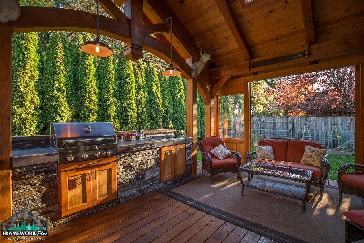 A wooden gazebo with a grill and a couch in it.