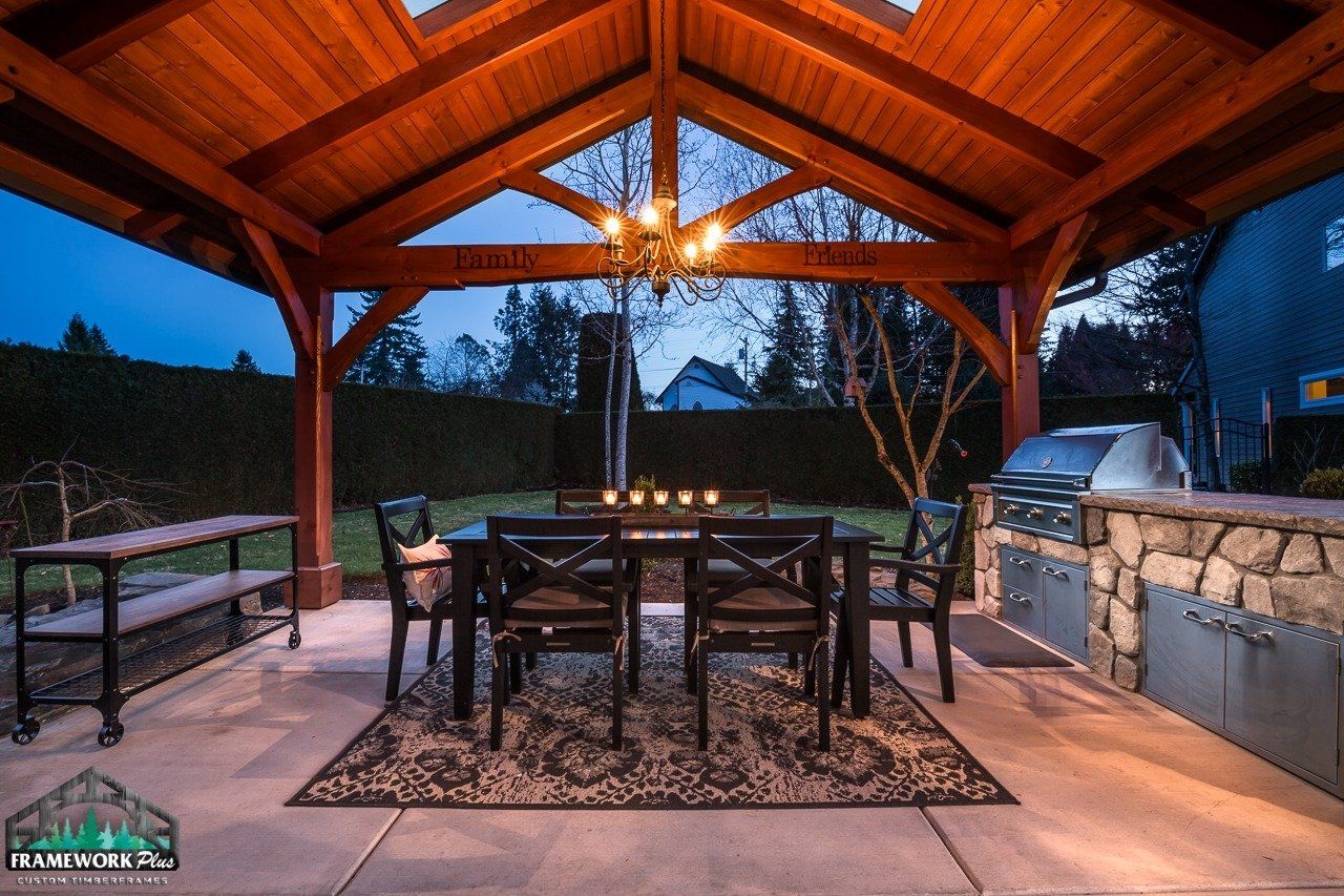 A patio with a table and chairs under a wooden roof