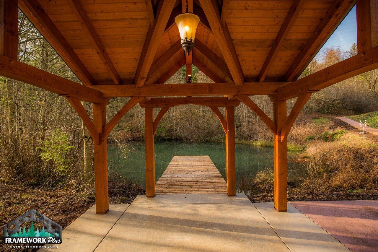A wooden gazebo overlooking a lake with a dock in the background.