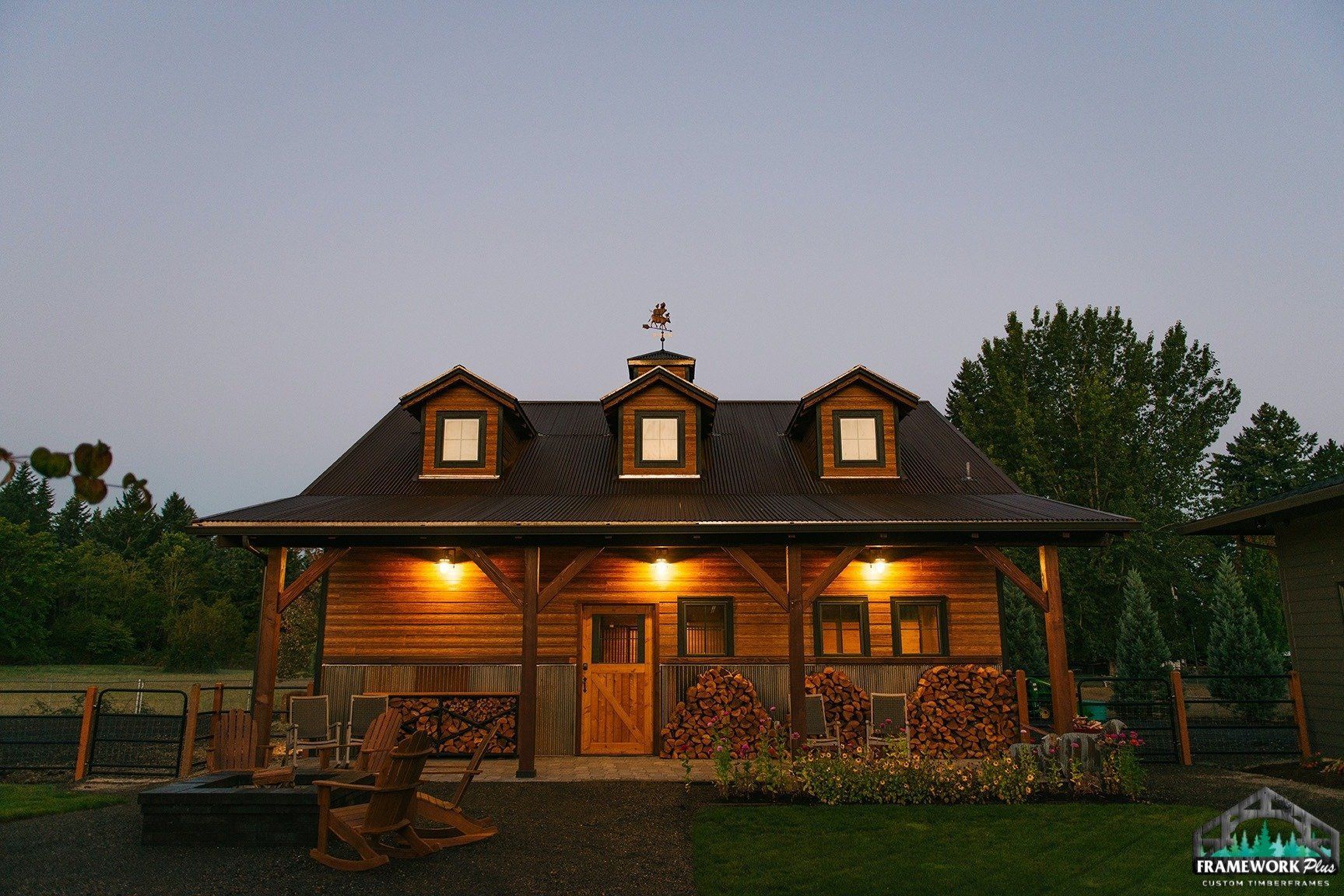 A large wooden house with a porch is lit up at night.