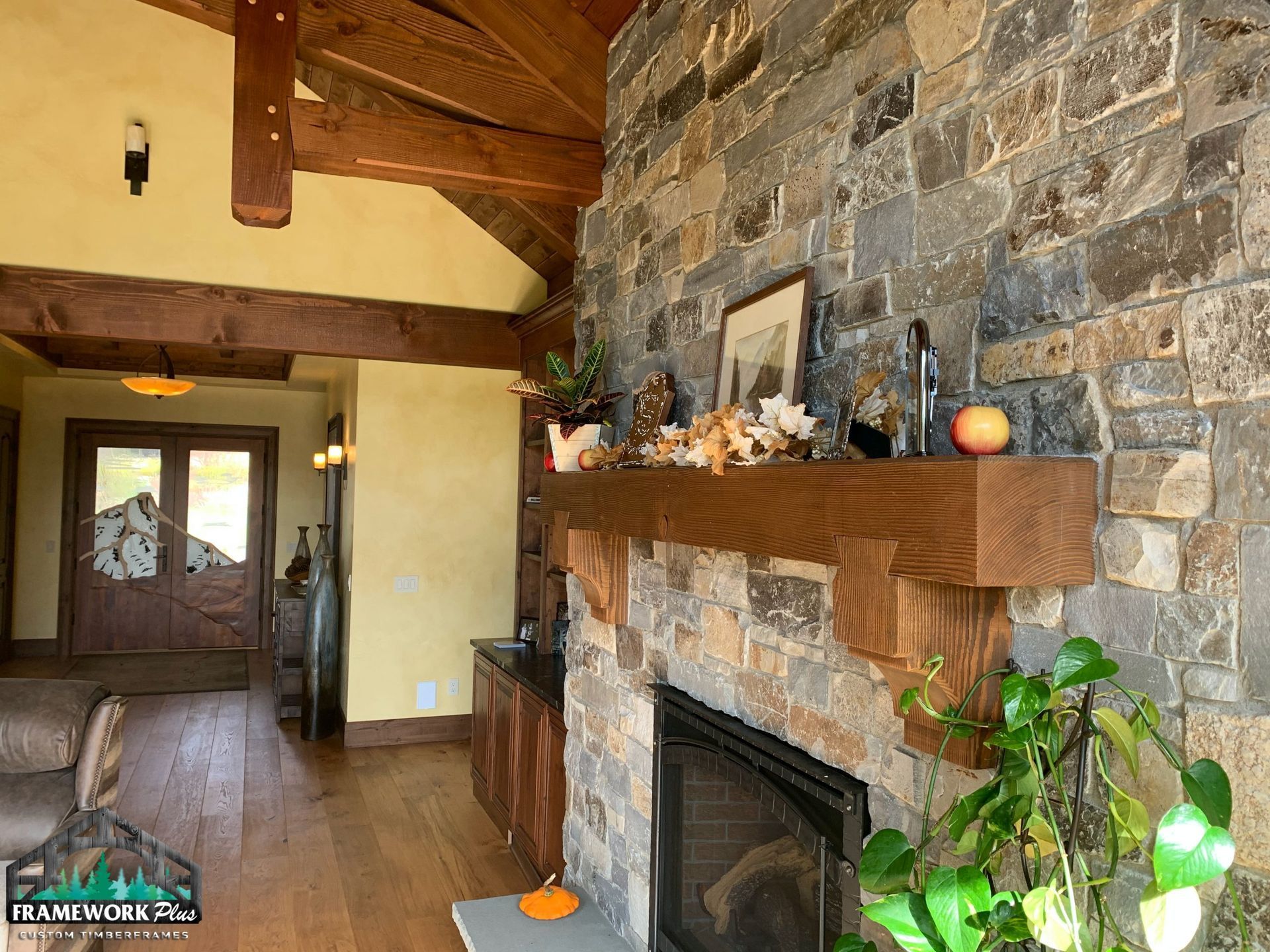A living room with a stone fireplace and a wooden mantle.