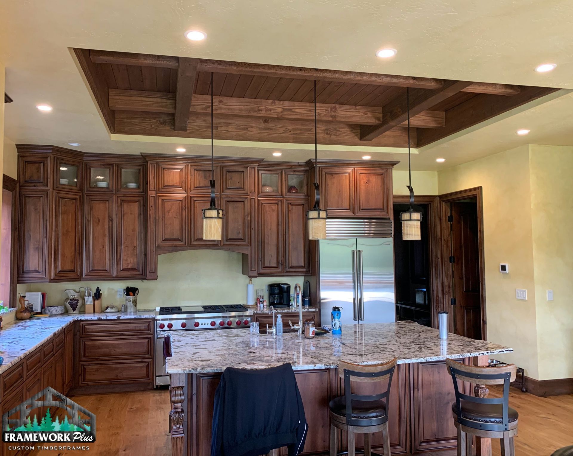 A kitchen with wooden cabinets , granite counter tops , stainless steel appliances and a large island.