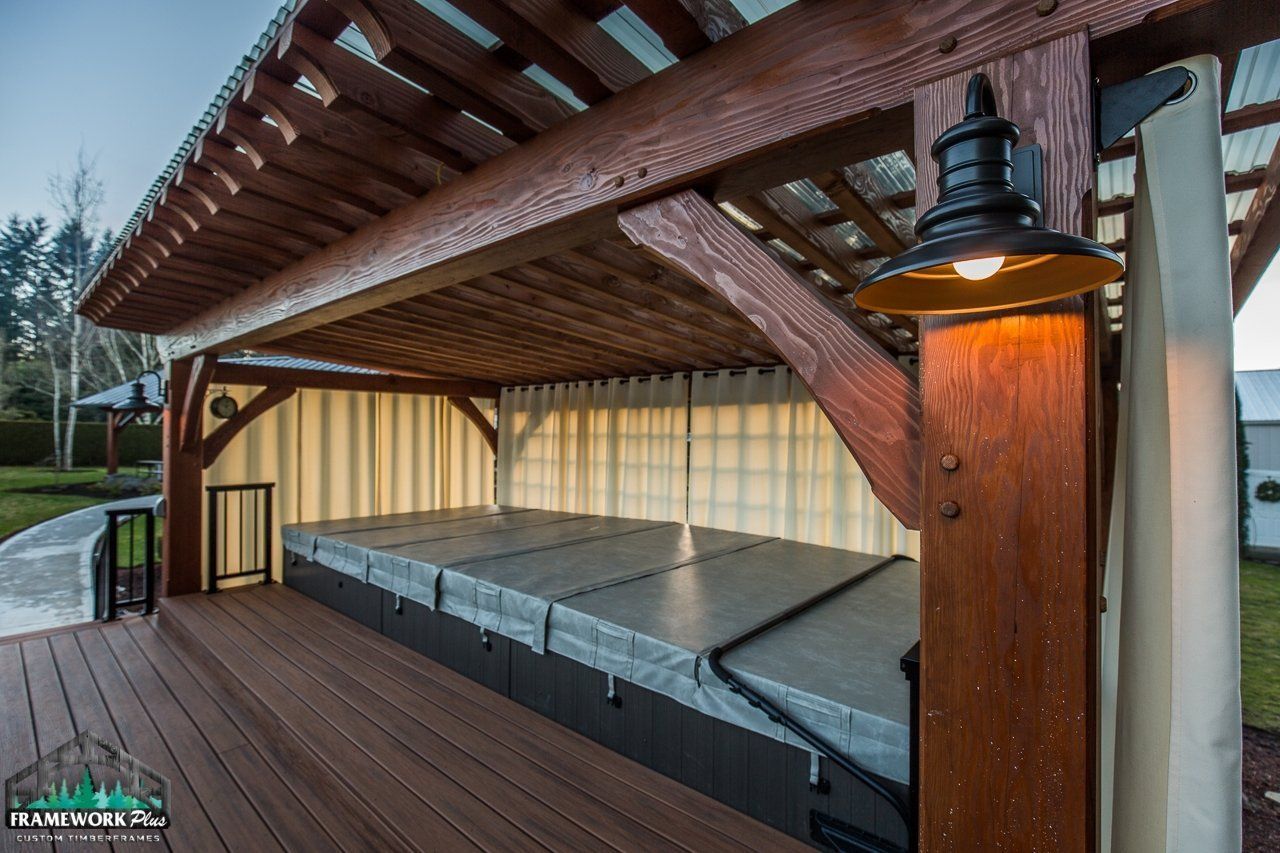 A wooden gazebo with a hot tub underneath it.