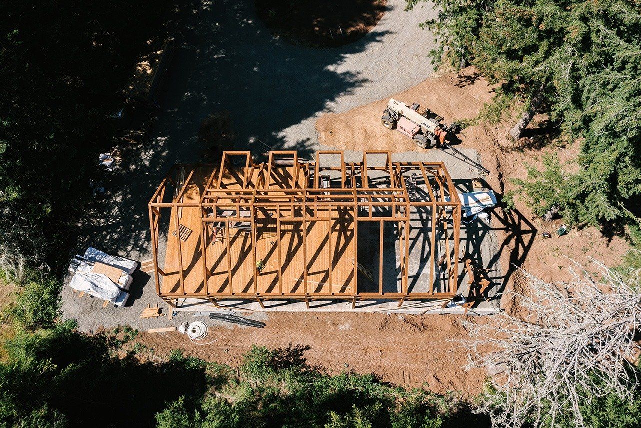 An aerial view of a building under construction in the middle of a forest.