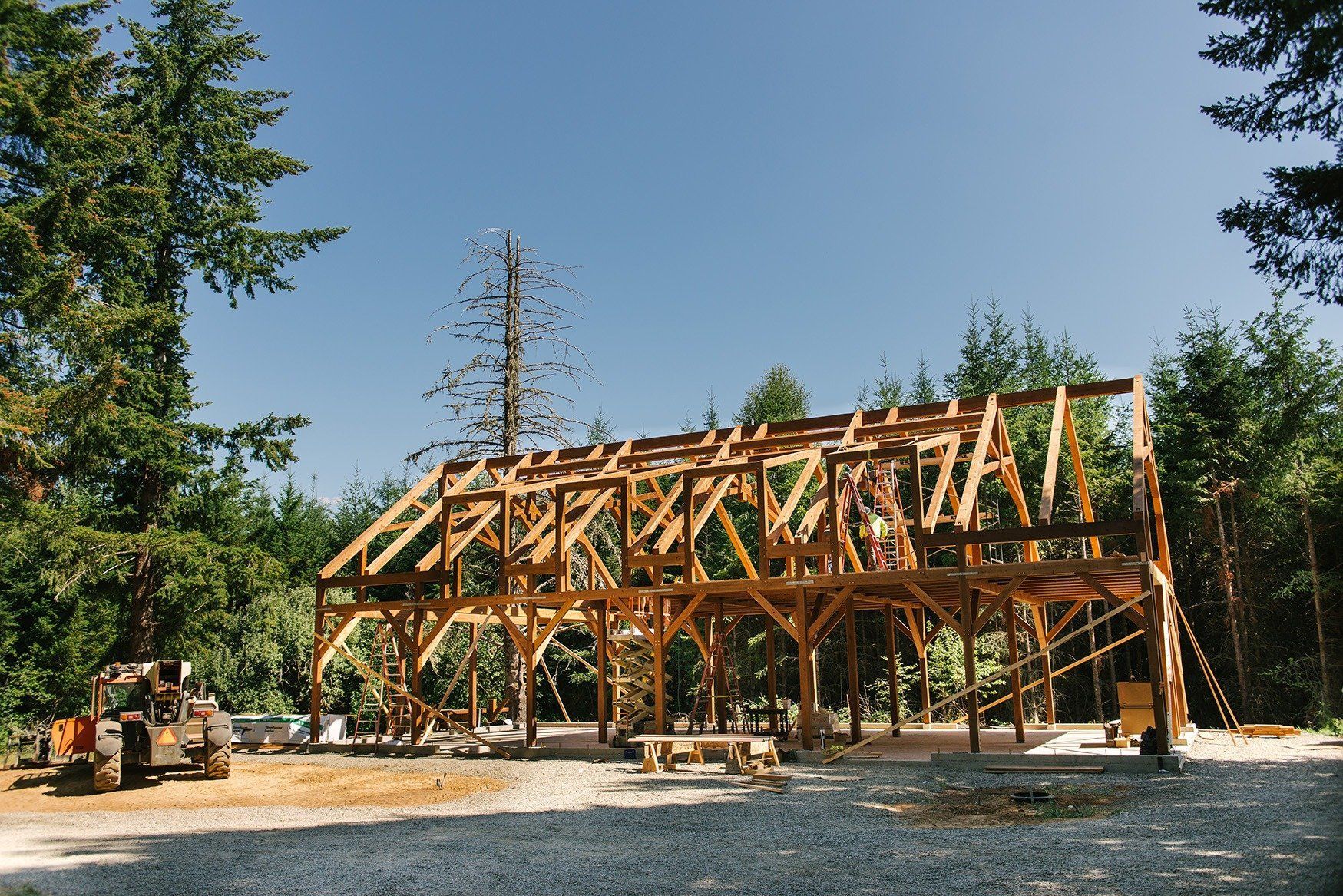 A large wooden structure is being built in the middle of a forest.