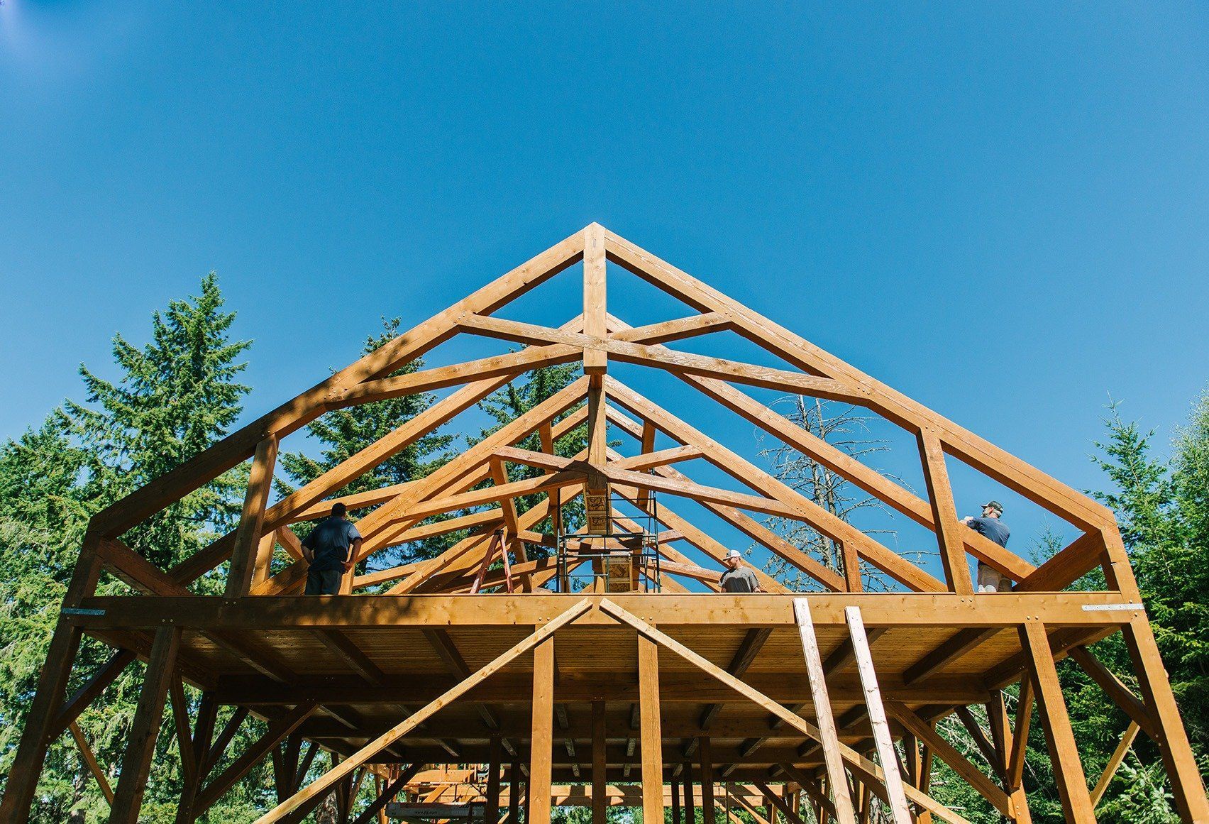 A wooden structure is being built with a blue sky in the background.