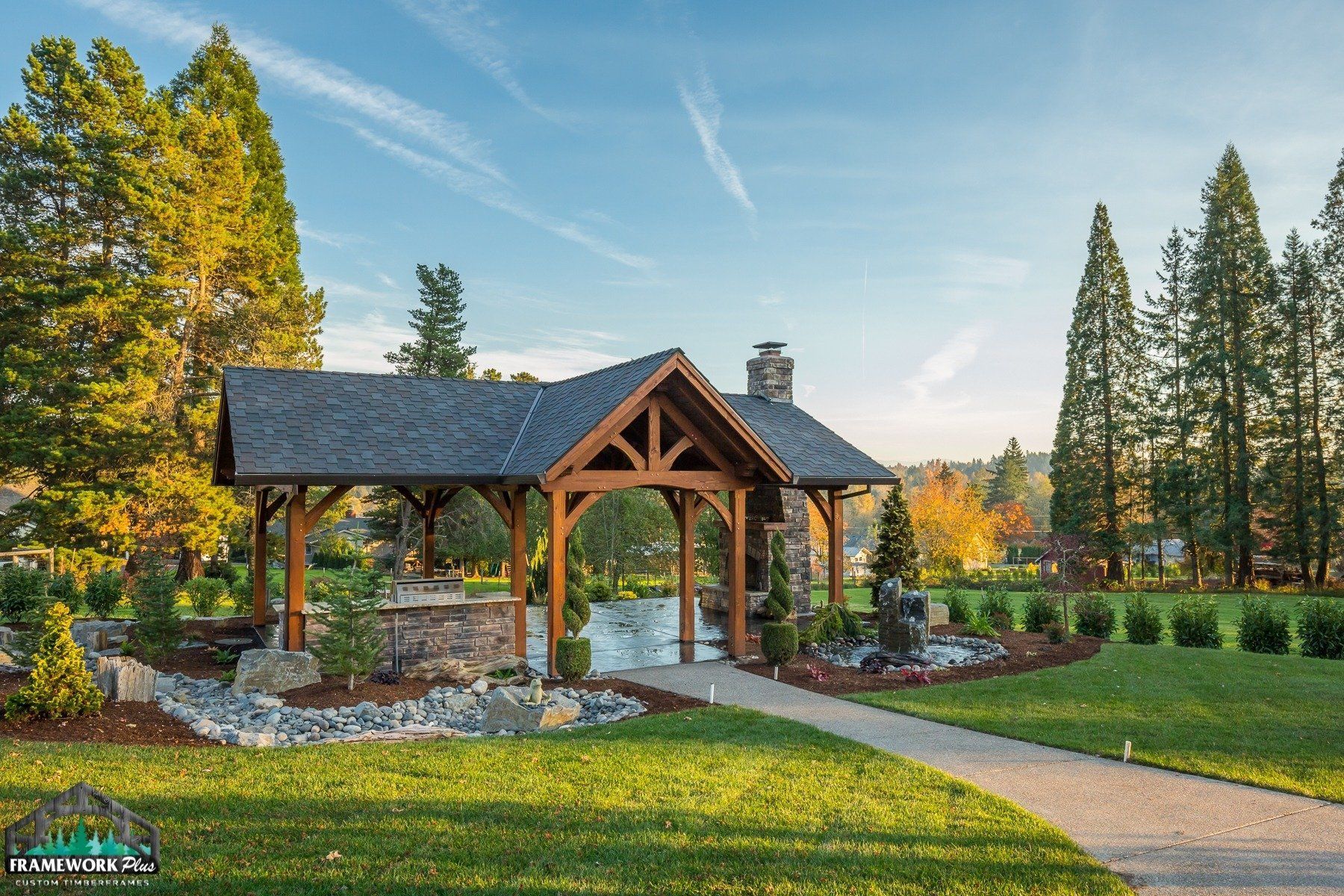 A wooden pavilion in the middle of a park with trees in the background.