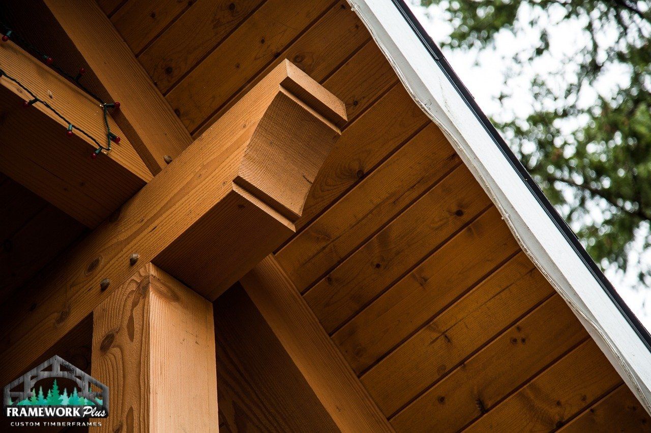 A close up of a wooden structure with a roof and trees in the background.