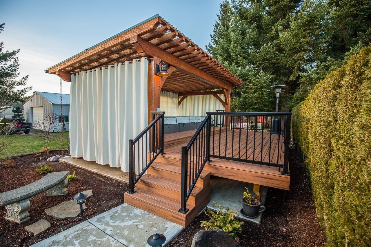 A wooden gazebo with a deck and stairs leading to it.