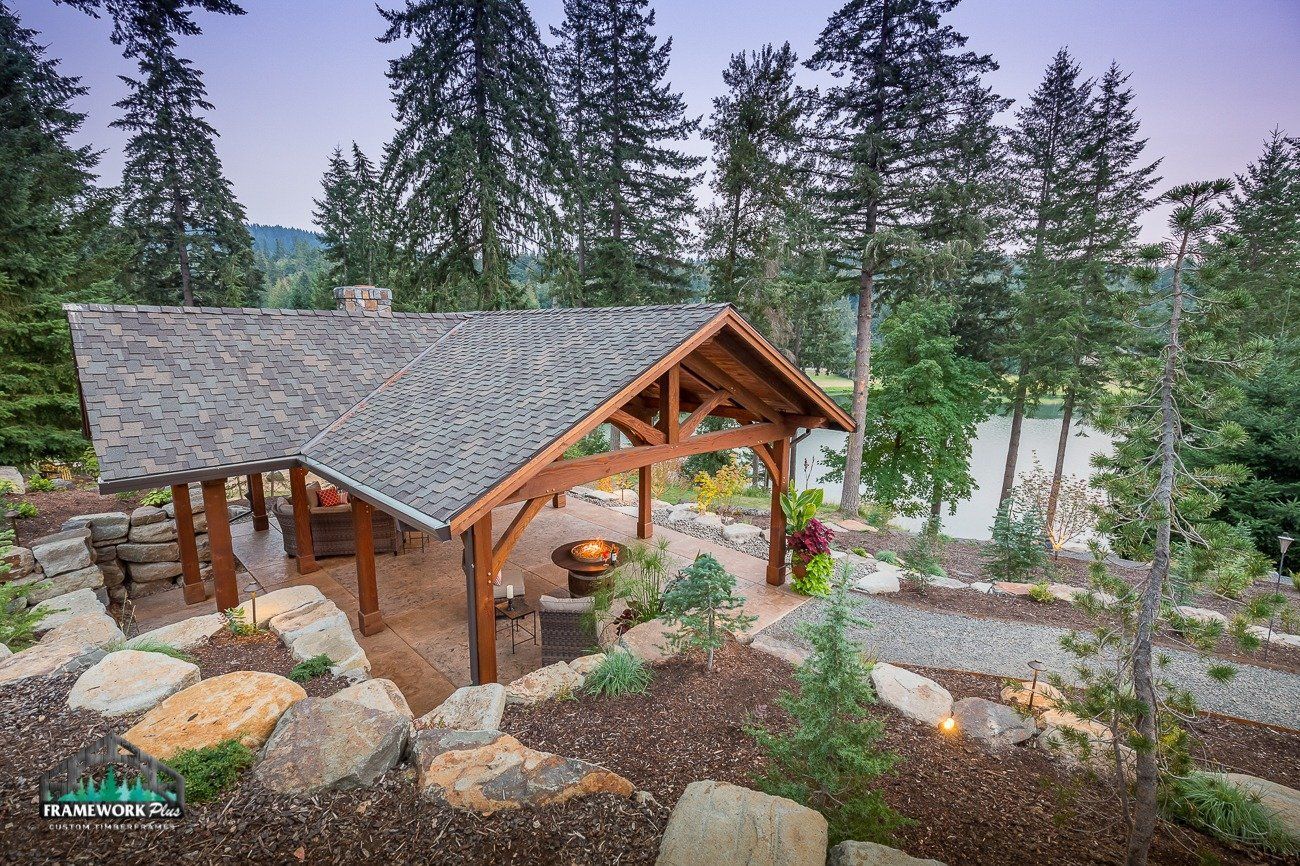 A wooden pavilion is surrounded by trees and rocks in the middle of a forest.