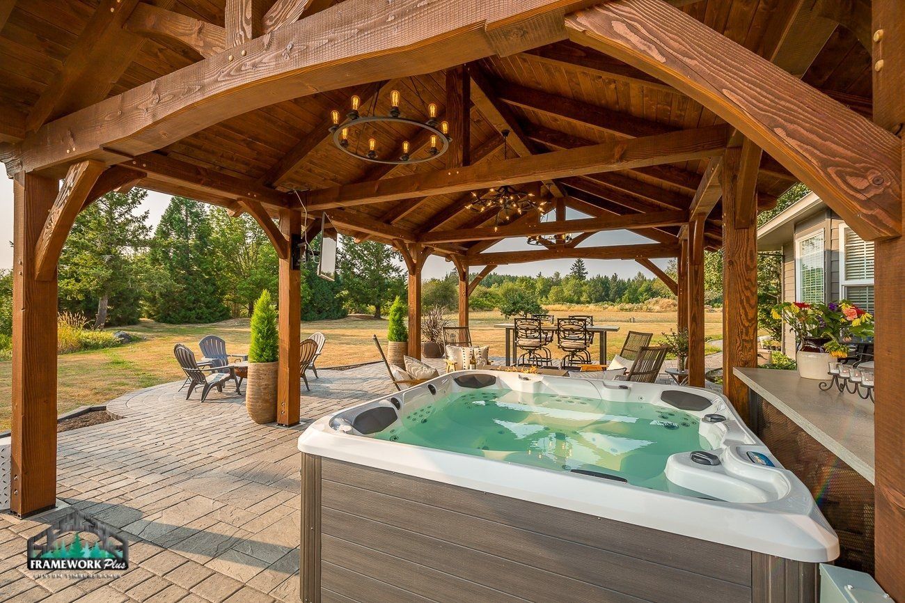 A hot tub is sitting under a wooden gazebo.