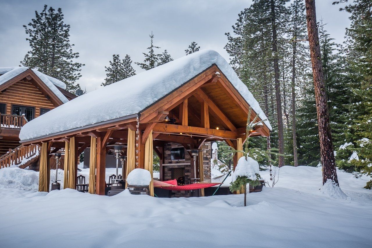 A wooden house covered in snow with trees in the background