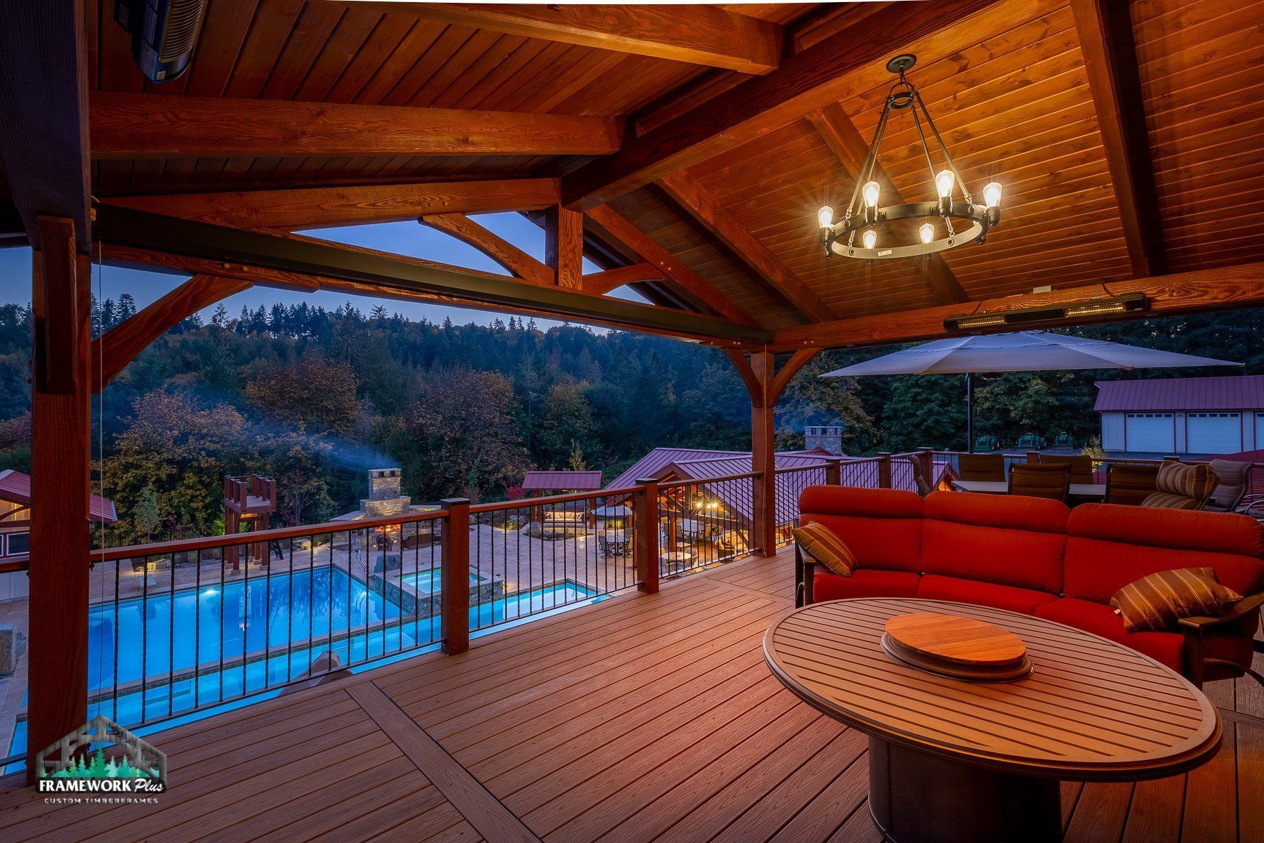 A wooden deck with a couch and a table with a view of a pool.