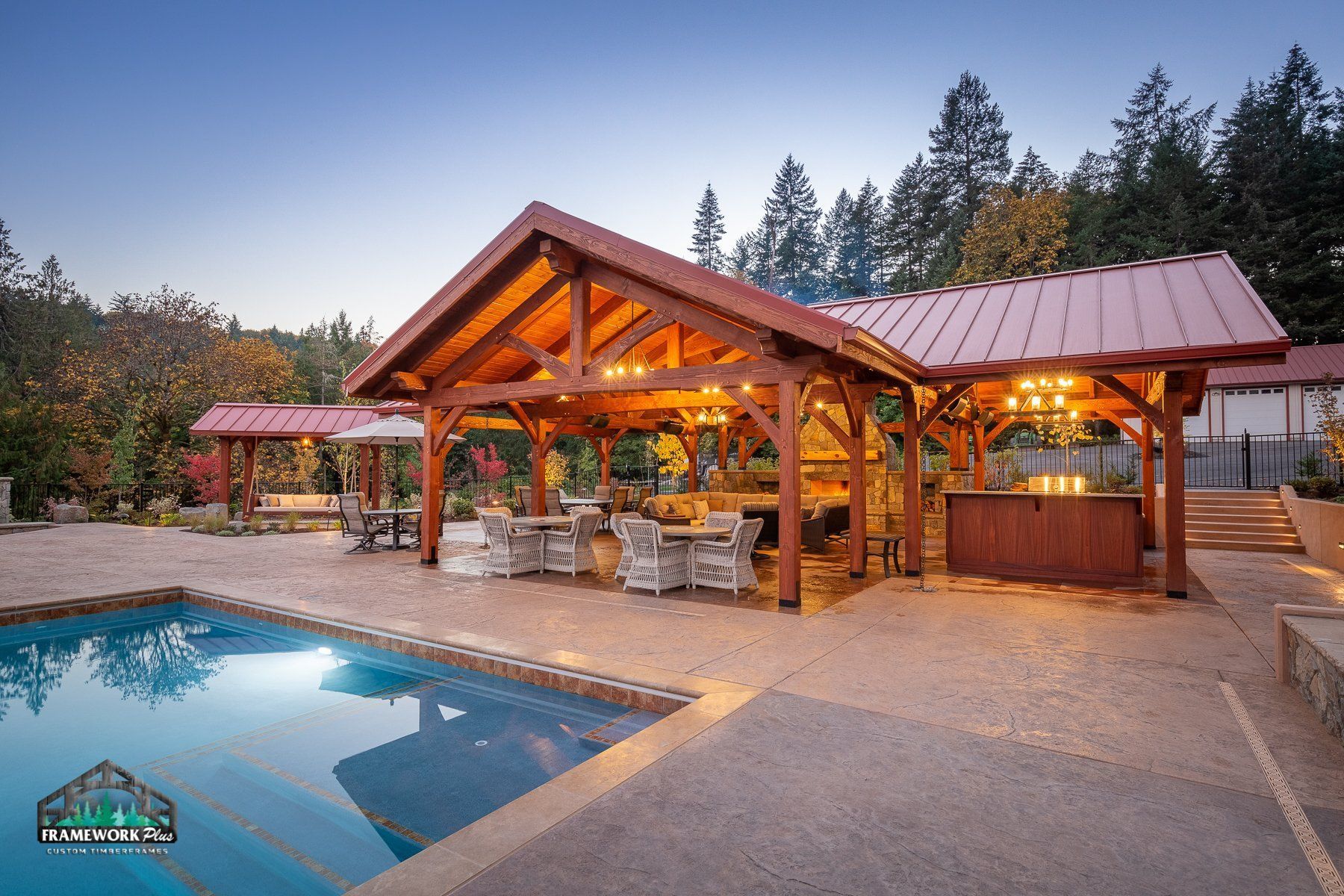 A large wooden pavilion with a swimming pool in front of it.