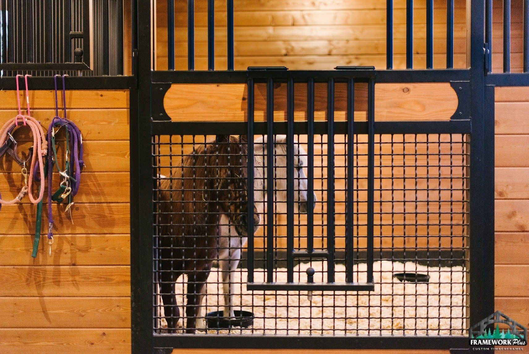 A horse is standing in a fenced in area in a barn.