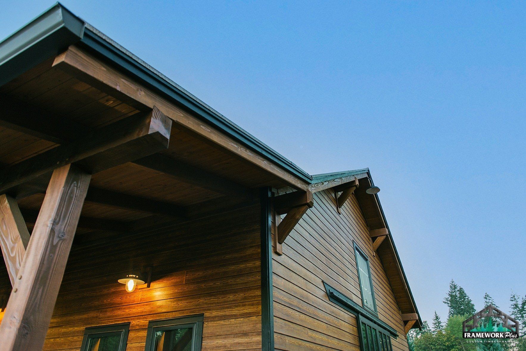 A wooden house with a porch and a blue sky in the background.