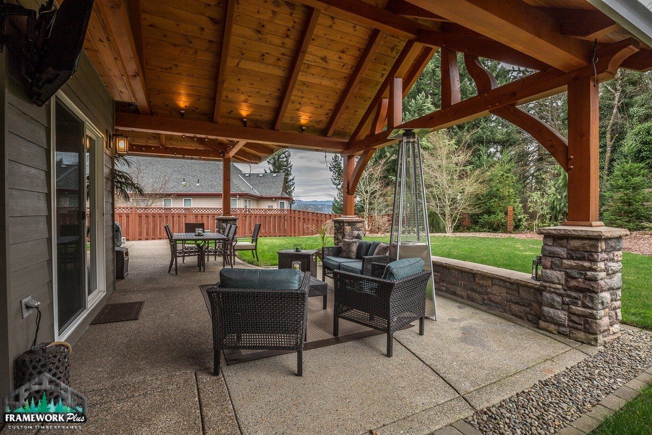 A large covered patio with a table and chairs under a wooden roof.