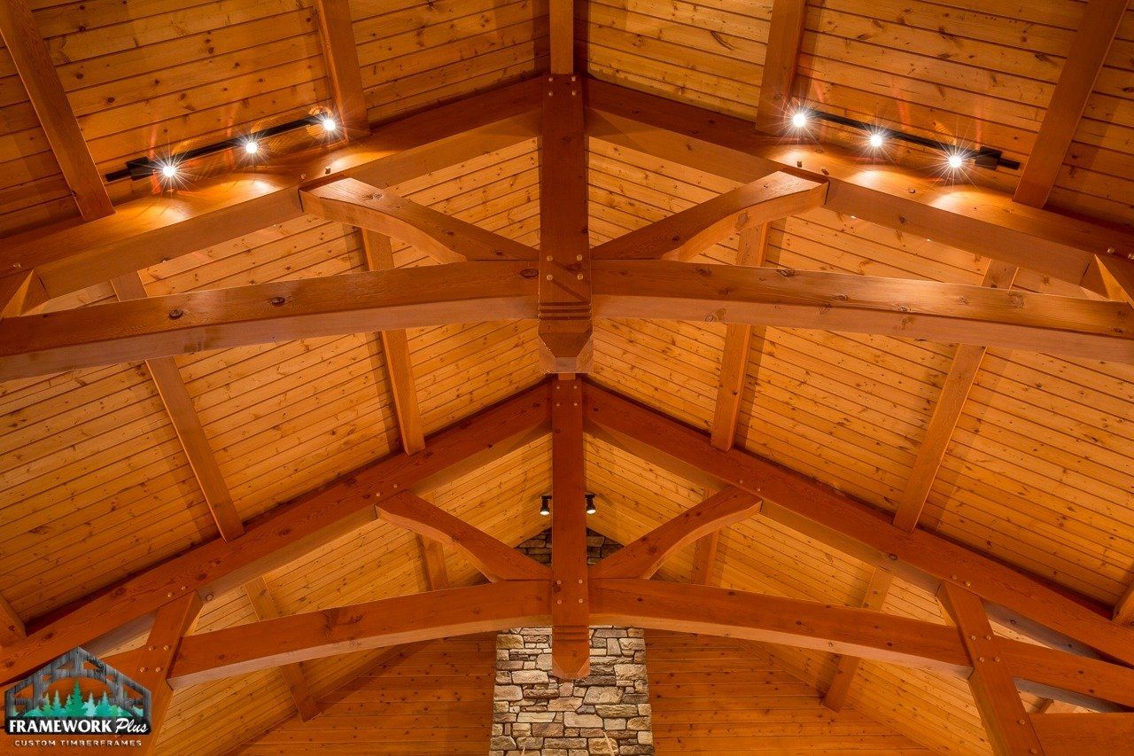 The ceiling of a building with wooden beams and a stone chimney.