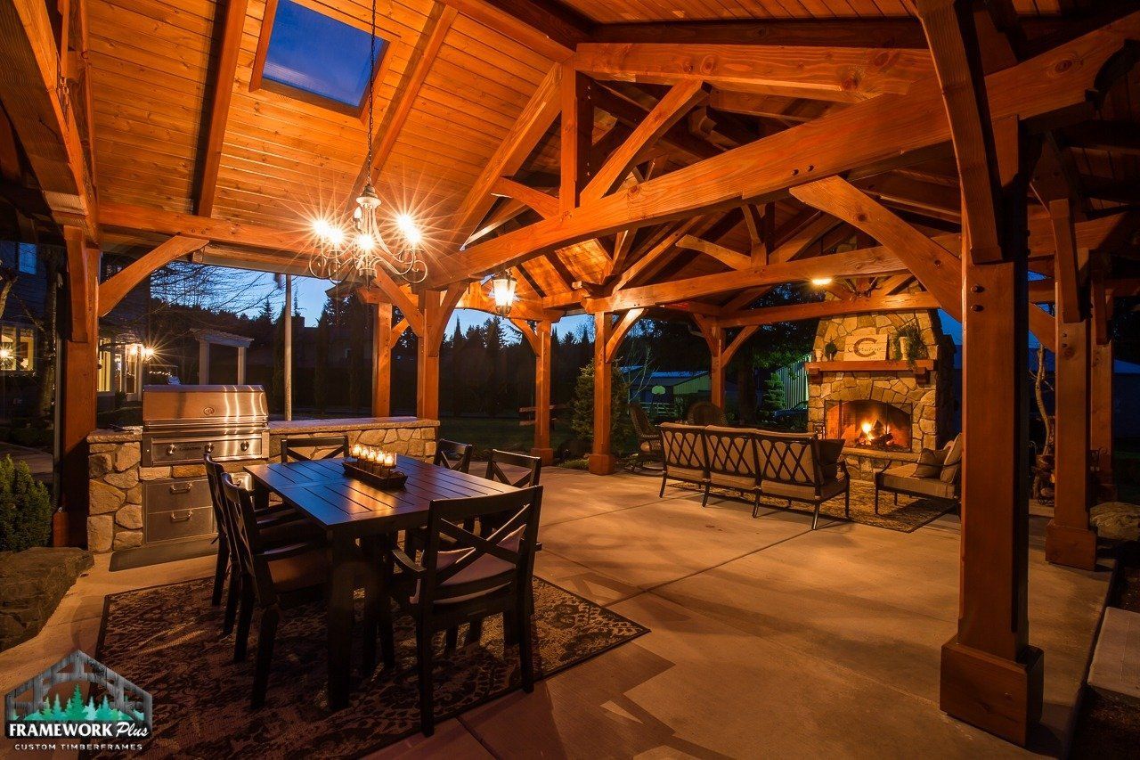 A large covered patio with a table and chairs and a fireplace.