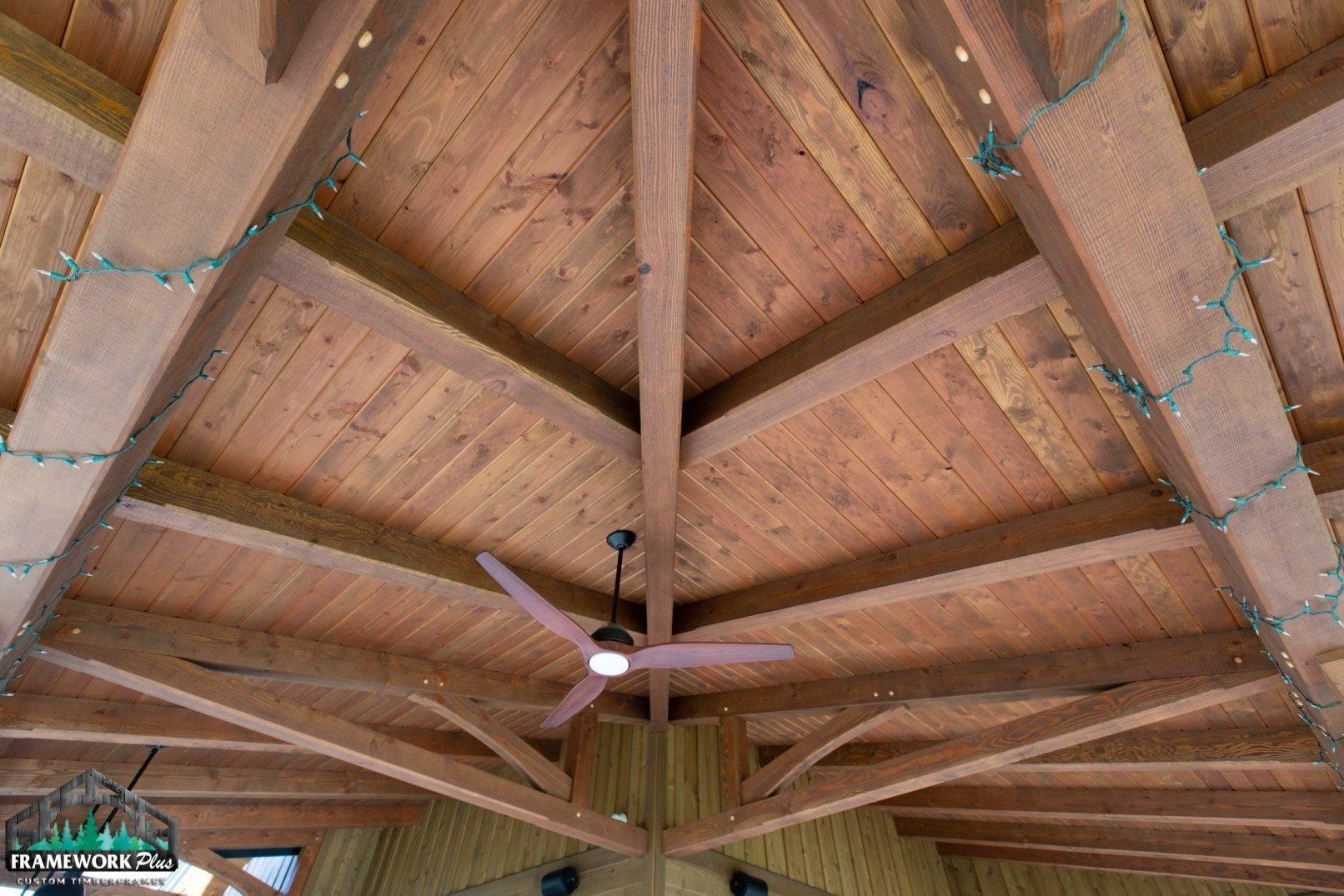 A ceiling fan is hanging from the ceiling of a wooden structure.