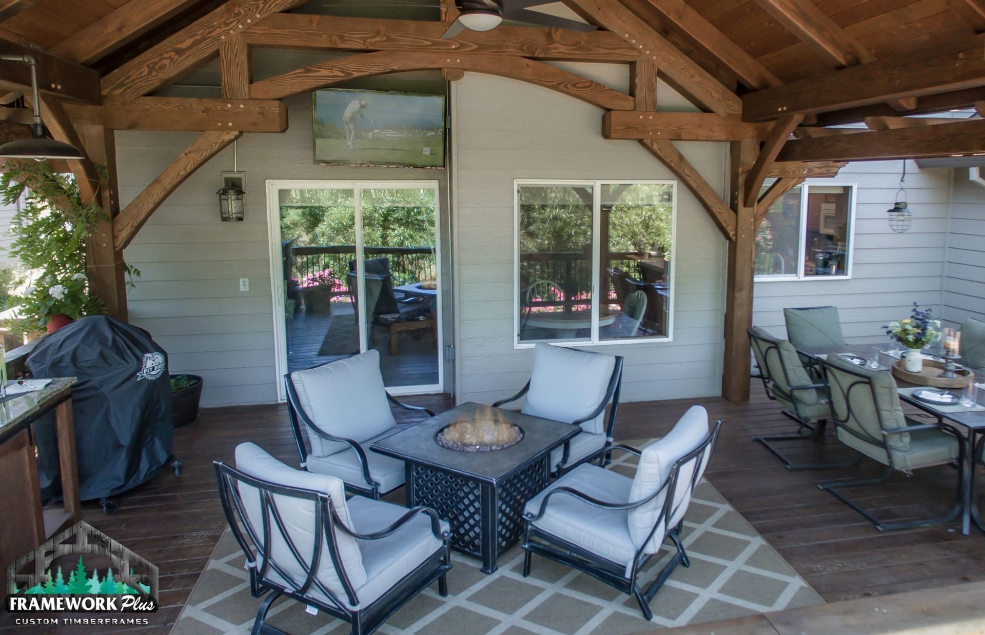 A patio with a fire pit , chairs , tables and a television.