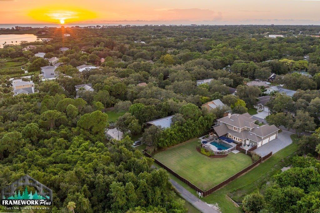 An aerial view of a house in the middle of a lush green forest.