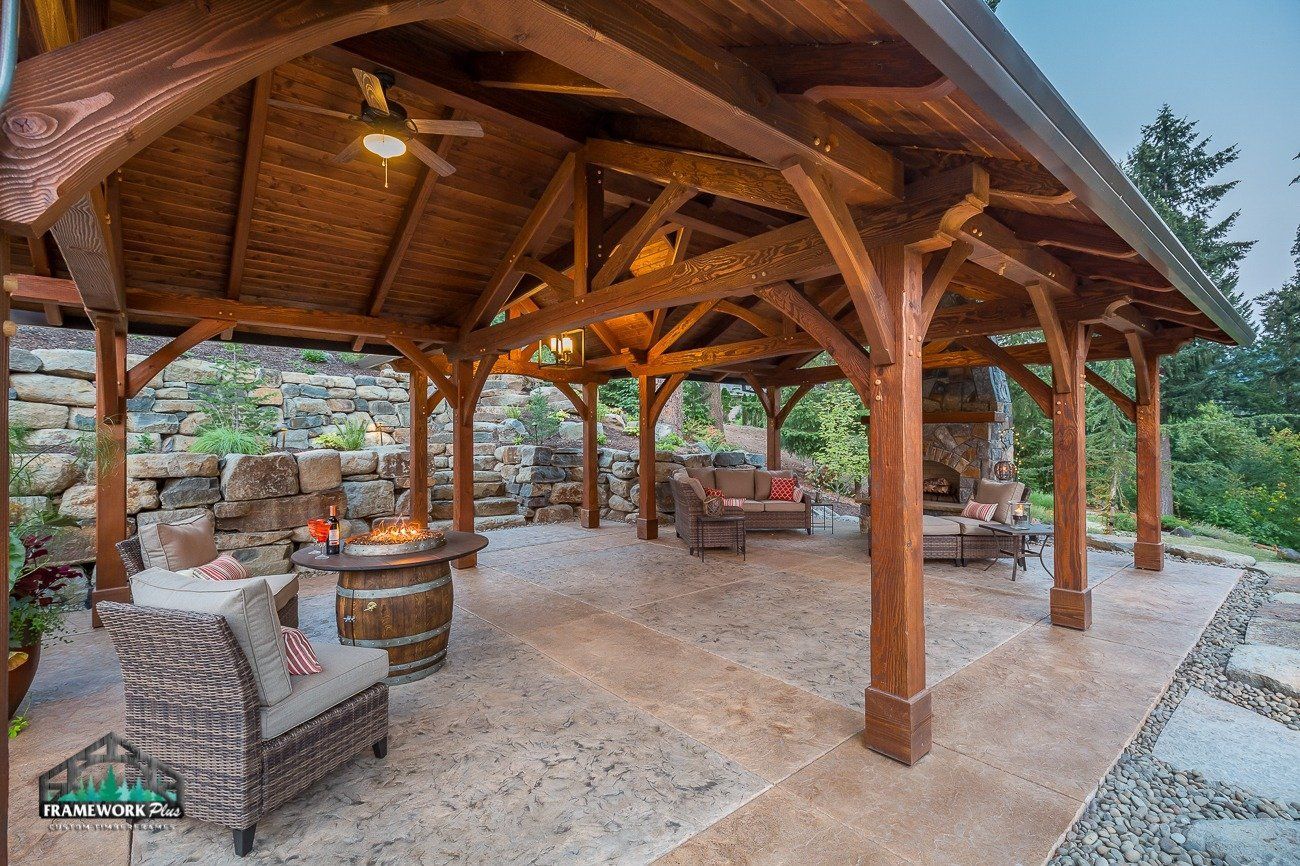 A large wooden pavilion with furniture and a fire pit.